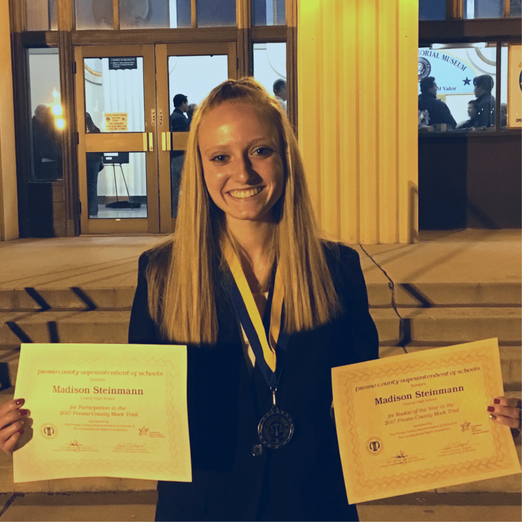 portrait of Steinmann with medals and certificates from a Mock Trial competition