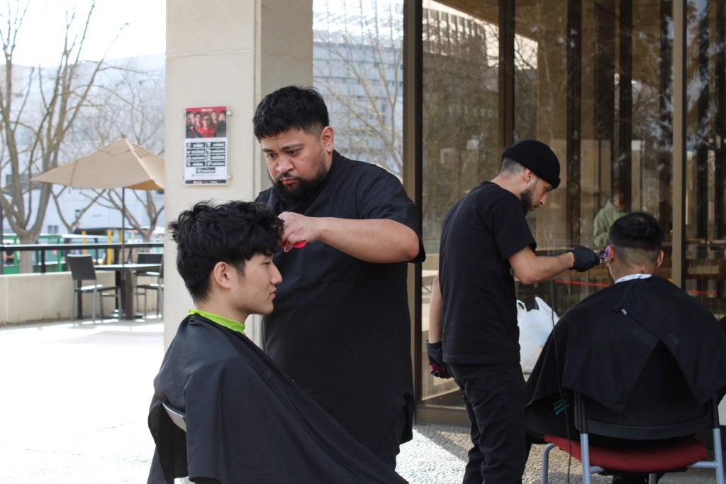 a student getting a haircut from a barber