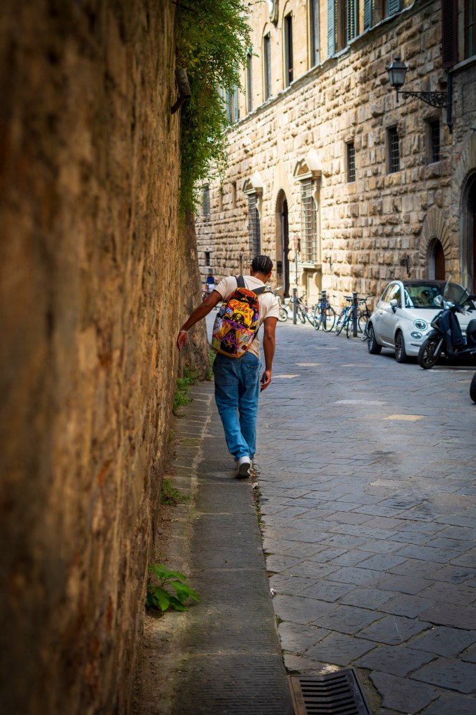 Kaden Watson walking along a narrow road in Florence. 