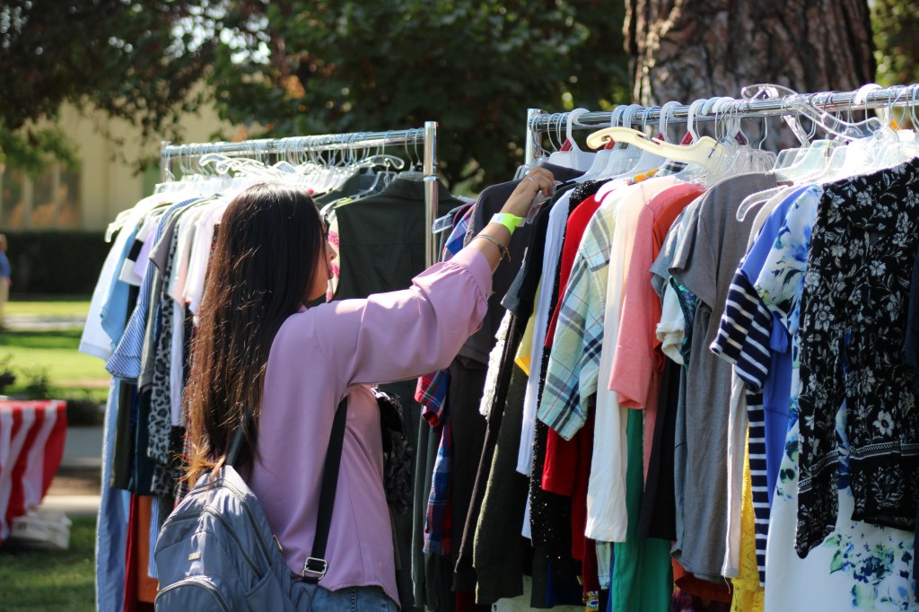 student sorts through racks of clothes