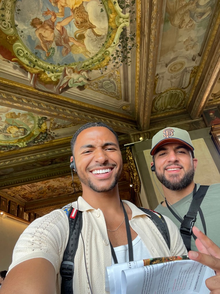 Watson and a friend take a selfie with historic artwork in the background
